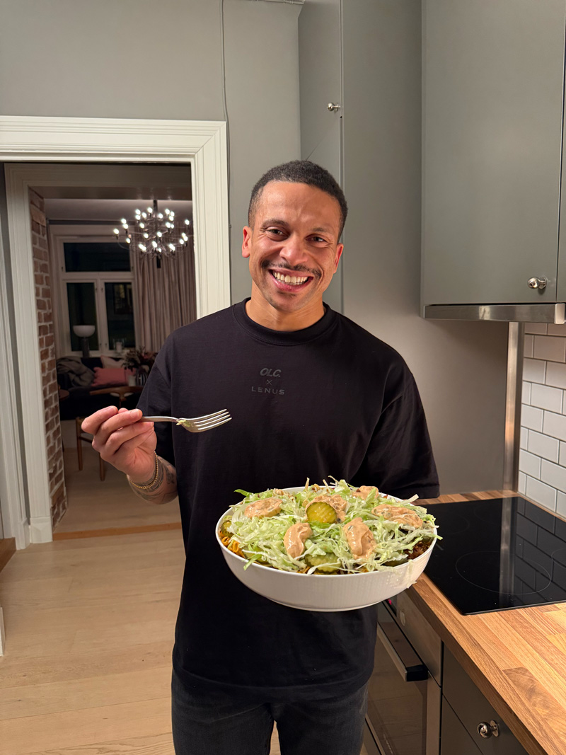 Treneren peker på seg selv med et smil